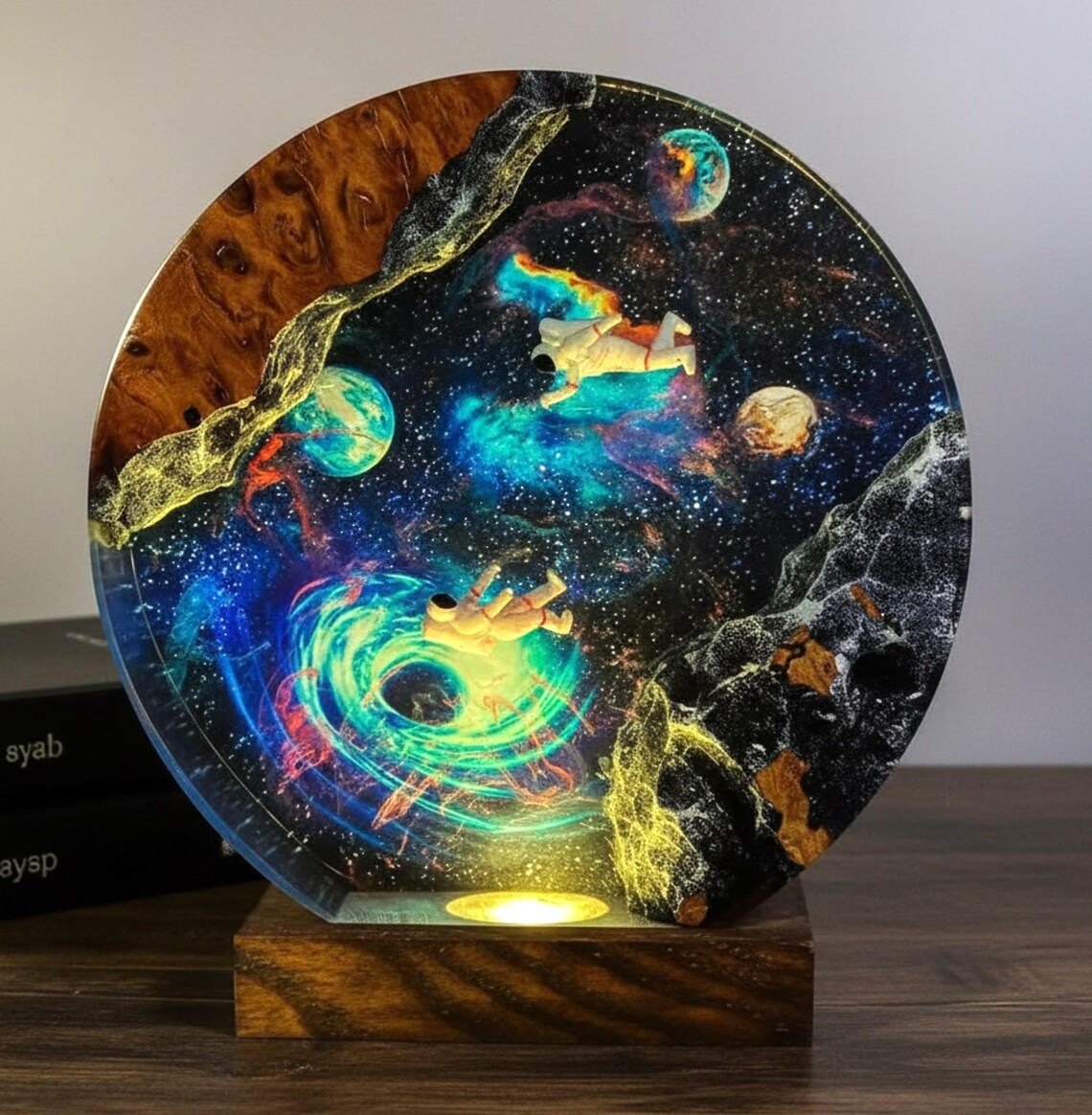 Astronaut black hole resin lamp glowing yellow-green beside books