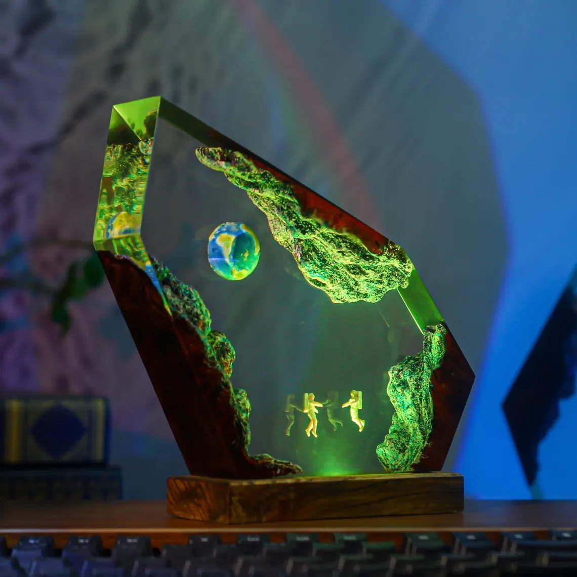 Astronaut galaxy resin lamp in green light beside a keyboard