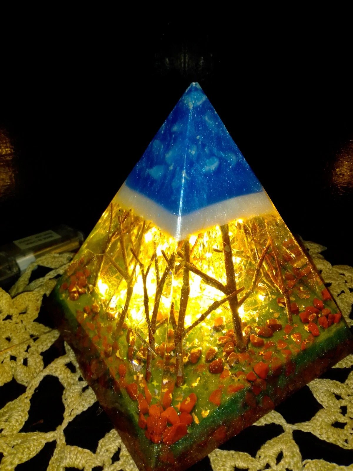 Forest resin pyramid lamp glowing warm, corner view