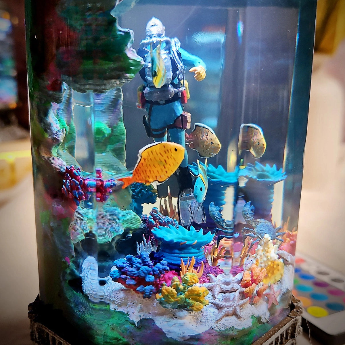 Close-up of scuba diver, tropical fish and coral inside the resin