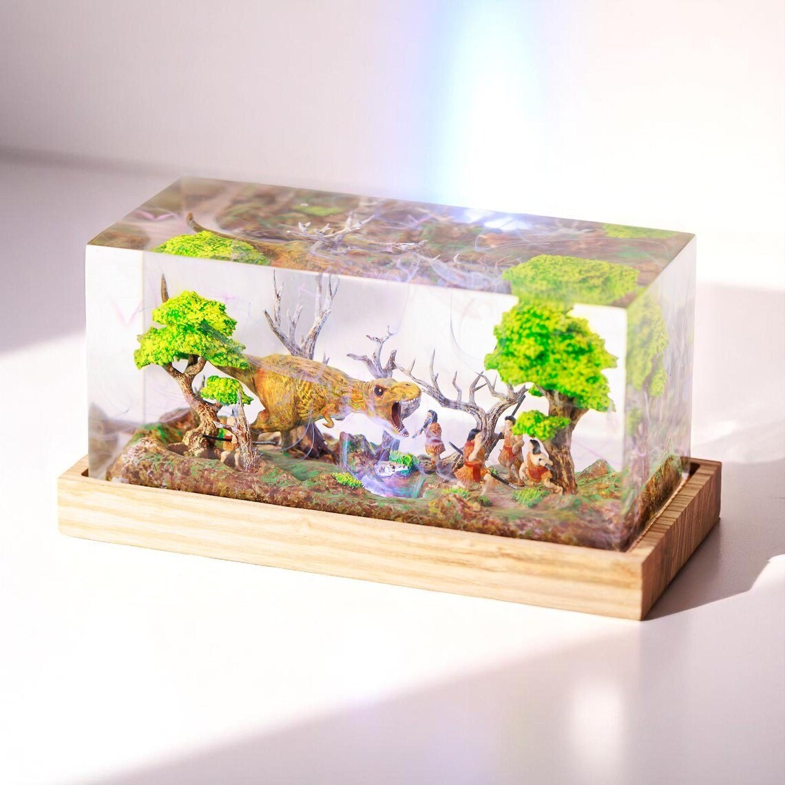 Clear epoxy dinosaur diorama block on a light wood tray