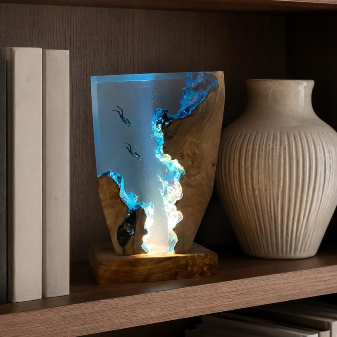 Scuba diver resin lamp glowing on a bookshelf beside a vase
